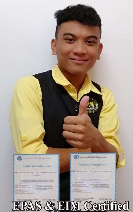 A student showing his certificates, smiling and giving a thumbs up