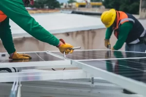 Two men installing solar panels on a rooftop