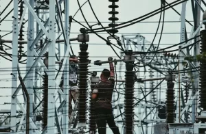 Workers inspect power tower connection